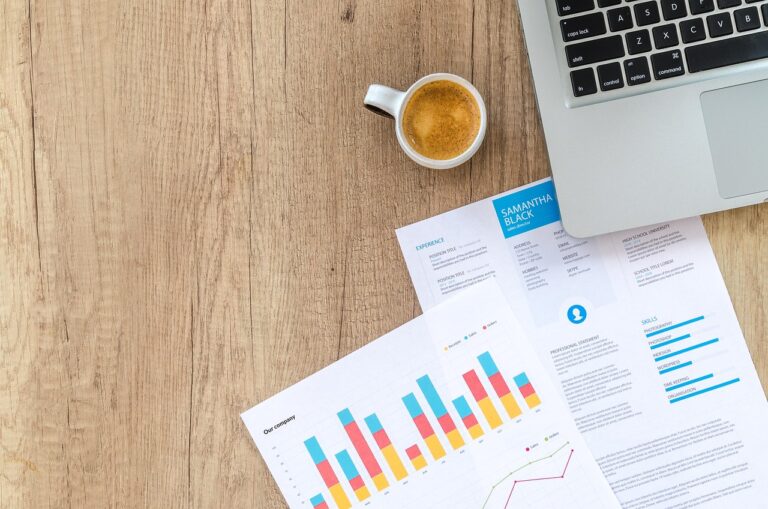 Persoon die bankafschriften doorneemt aan een bureau om vaste lasten overzicht te maken