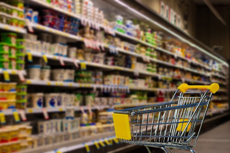 Winkelwagen in een supermarktpad omringd door volle schappen